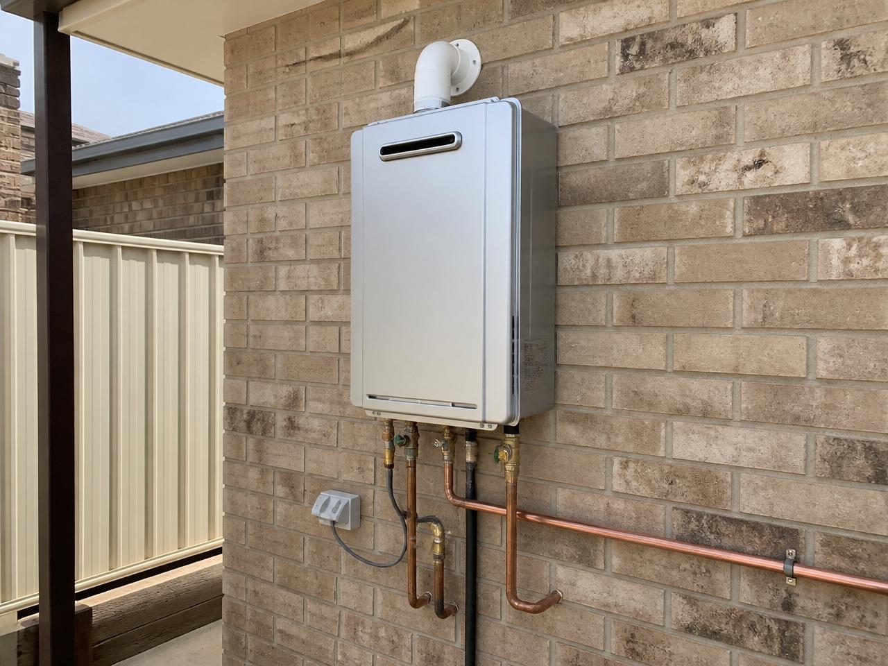 An illustrative residential property with a hot water system installed against an exterior wall.